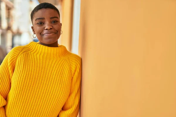 Genç Afrikalı Amerikalı kadın gülümseyerek şehirde mutlu mesut duruyor..