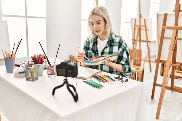 Genç ressam kız mutlu resim çiziyor. Sanat atölyesindeki masa başı resim dersinde otururken..