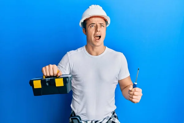 Handsome Young Man Holding Toolbox Screwdriver Angry Mad Screaming Frustrated — Stockfoto