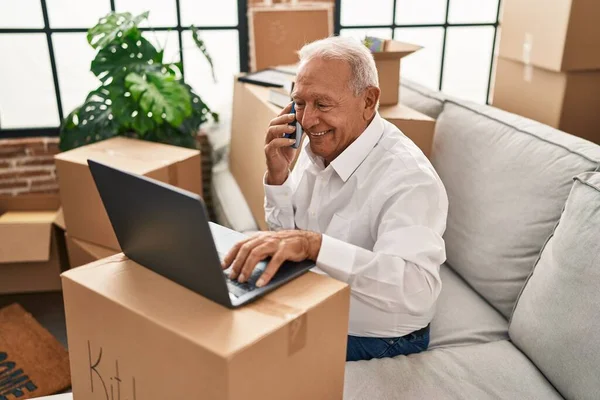 Hombre Mayor Usando Ordenador Portátil Hablando Teléfono Inteligente Nuevo Hogar — Foto de Stock