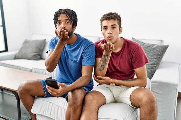 Jóvenes Hombres Hispanos Usando Teléfono Inteligente Sentado Sofá Casa Mirando —  Fotos de Stock