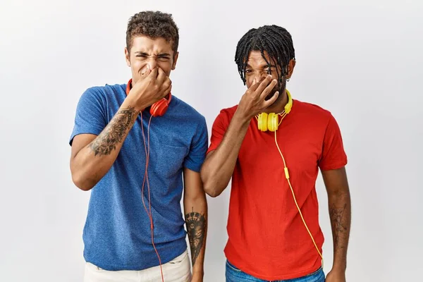 Young Hispanic Brothers Standing Isolated Background Wearing Headphones Smelling Something — Stok fotoğraf