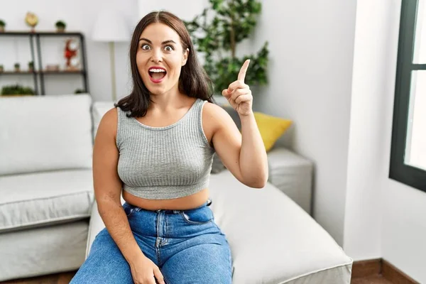 Young Brunette Woman Sitting Sofa Home Pointing Finger Successful Idea — Stockfoto