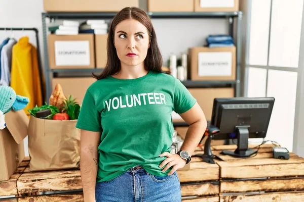 Bağışta gönüllü tişört giyen genç esmer kadın uykulu ve yorgun görünüyor, yorgunluktan yorgun ve akşamdan kalma, sabahları tembel gözler.. 