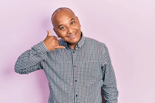 Orta yaşlı, sıradan kıyafetler giyen, gülümseyen, el ve parmaklarıyla telefonla konuşan Latin bir adam. iletişim kavramları. 