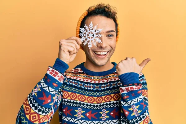 Young Handsome Man Holding Snowflake Wearing Winter Sweater Pointing Thumb — Stock Fotó