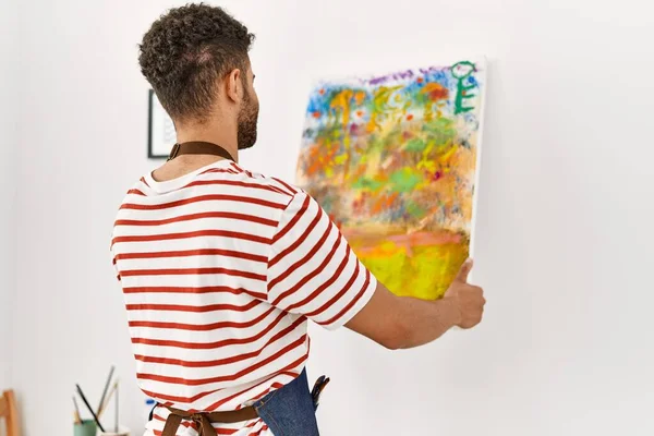 在艺术工作室 年轻的阿拉伯艺术家坐在后视镜下 挂在墙上画画布 — 图库照片