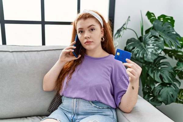 Young Redhead Woman Talking Smartphone Holding Credit Card Home — Stockfoto