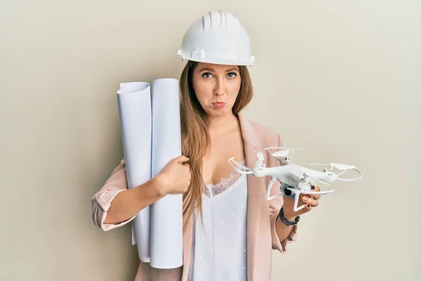 Jonge Blonde Vrouw Met Een Veiligheidshelm Met Blauwdrukken Drone Depressief — Stockfoto