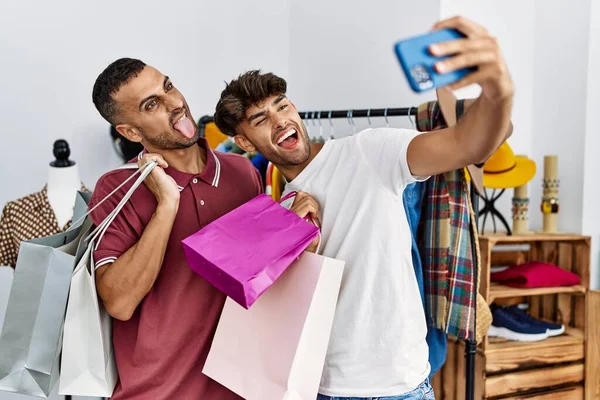 İki İspanyol müşteri alışveriş torbaları tutuyor ve giyim mağazasındaki akıllı telefonun yanında selfie çekiyor..