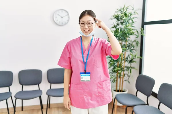 Joven Asiática Enfermera Mujer Sala Espera Médica Sonriendo Señalando Cabeza —  Fotos de Stock