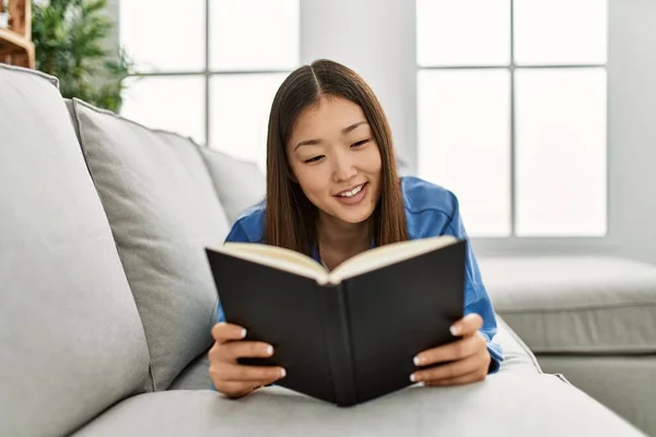 Ung Kinesisk Flicka Läser Bok Liggande Soffan Hemma — Stockfoto