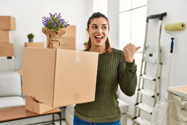 Young Hispanic Woman Holding Cardboard Box Moving Pointing Thumb Side — Fotografia de Stock