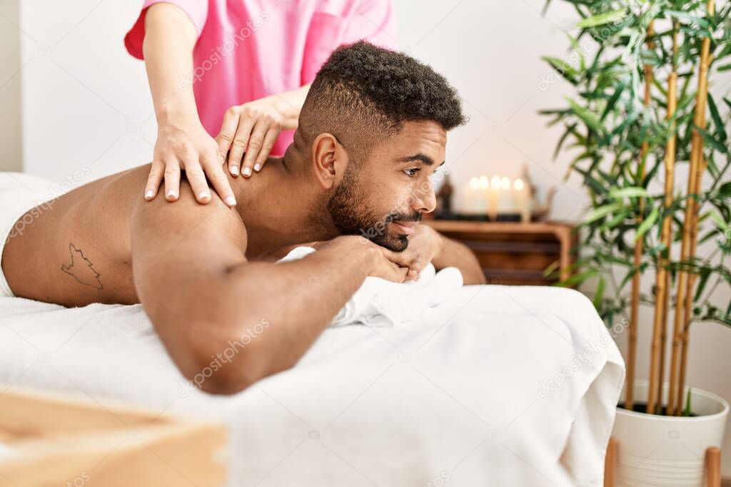 Young african american smiling happy reciving back massage at beauty center.