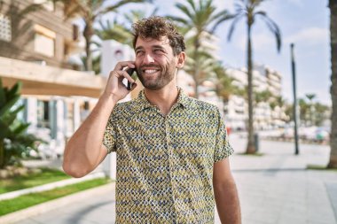 Genç İspanyol adam gülümsüyor. Kendine güveniyor. Sokakta akıllı telefondan konuşuyor.