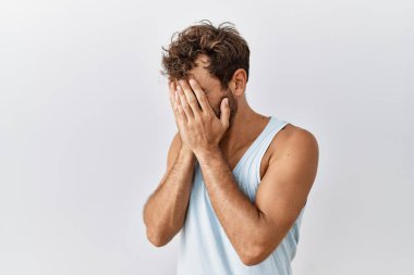 Genç yakışıklı adam izole edilmiş arka planda duruyor. Ağlarken yüzünü ellerle kapatan üzgün bir yüz ifadesi var. Depresyon kavramı. 