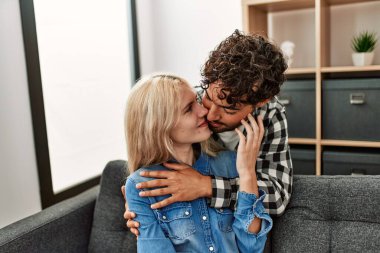 Kanepede oturan genç çift evde sarılıyorlar..