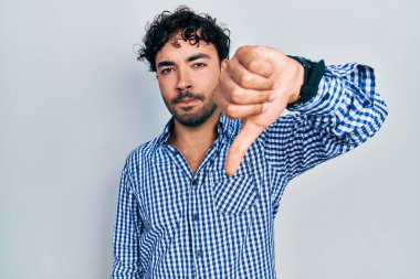 Gündelik kıyafetler giyen genç İspanyol adam mutsuz görünüyor ve reddediliyor ve olumsuz bir hareket yapıyor. kötü ifade. 