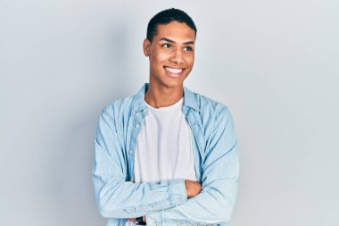 Genç Afro-Amerikalı, günlük kıyafetler giymiş, yüzünde gülümseme ve doğal bir ifadeyle yan yana bakıyor. Kendinden emin gülen. 