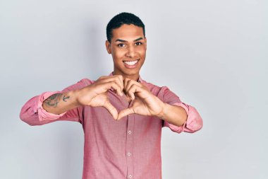 Genç Afro-Amerikan adam, günlük kıyafetler giyip, aşkla gülümsüyor. Elleriyle kalp sembolü ve şekli gösteriyor. romantik kavram. 