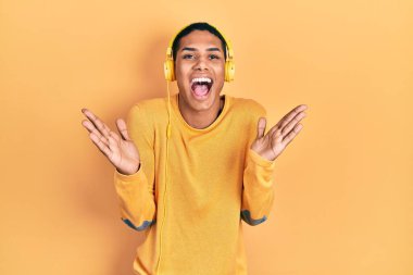 Kulaklıkla müzik dinleyen genç Afro-Amerikalı adam çılgın kutlamalar yapıyor ve kollarını kaldırıp heyecanla haykırarak başarıyı kutluyor. Kazanan konsept 