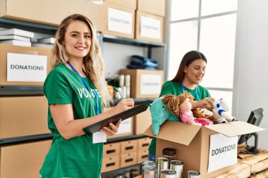 İki gönüllü kadın, hayır kurumunda çalışmaktan mutlu gülümsüyor..