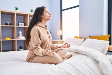 Genç İspanyol kadın yoga egzersizi yapıyor. Yatak odasında oturuyor.