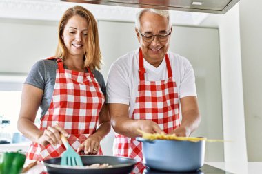 Orta yaşlı İspanyol çift mutfakta mutlu bir yemek pişiriyor..