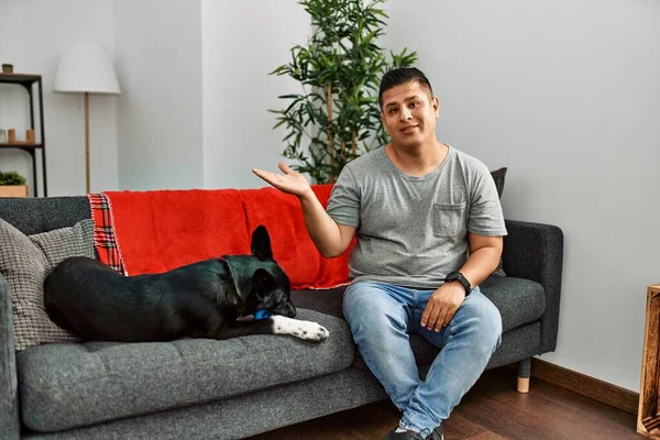 Young Latin Man Dog Sitting Sofa Home Smiling Cheerful Presenting — Stockfoto
