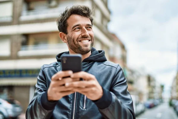 英俊而惊慌的男人 留着胡子 在户外用智能手机快乐地微笑 — 图库照片