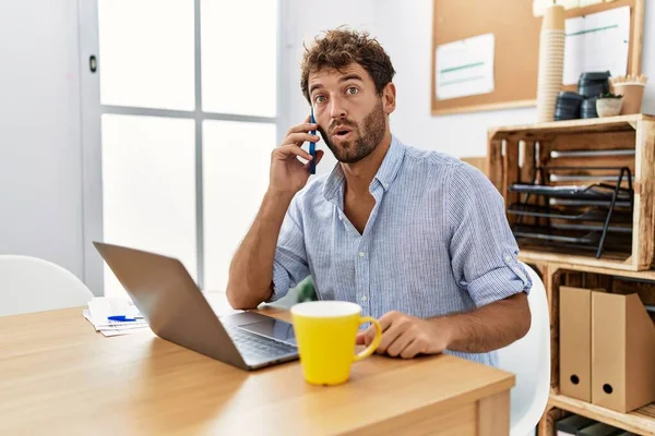 Young Handsome Man Working Office Speaking Phone Scared Amazed Open — стоковое фото