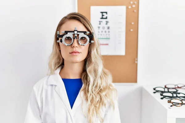 Young Beautiful Optician Woman Wearing Optometry Glasses Clinic Serious Expression — стоковое фото