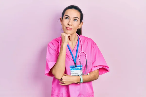 Doktor Üniforması Giyen Genç Esmer Kadın Eli Çenesinde Steteskop Soru — Stok fotoğraf