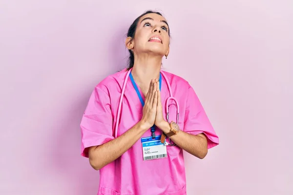 Young Brunette Woman Wearing Doctor Uniform Stethoscope Begging Praying Hands — стоковое фото
