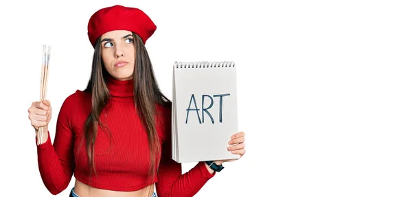 Young Brunette Teenager Holding Art Notebook Paintbrushes Smiling Looking Side — Foto de Stock