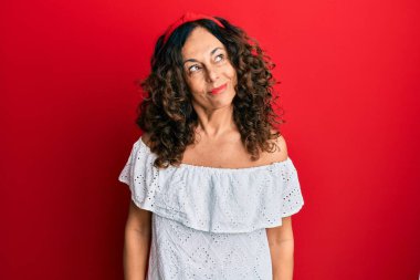 Orta yaşlı İspanyol kadın gündelik kıyafetler giyiyor gülümsüyor yan tarafa bakıyor ve düşünüyor.. 