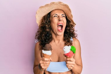 Orta yaşlı İspanyol bir kadın yaz tarzı giyinmiş elinde dondurmayla öfkeli ve öfkeli çığlıklar atıyor öfkeyle bağırıyor, öfkeyle yukarı bakıyor.. 