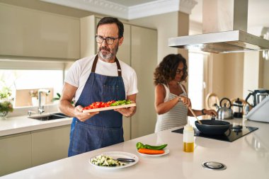 Orta yaşlı bir çift evde Akdeniz yemeği pişiriyor şüpheci ve gergin, sorun yüzünden somurtuyorlar. negatif kişi. 