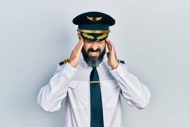Kafası ağrıdığı için uçak pilotu üniforması giyen genç İspanyol bir adam. migren ağrısı. 