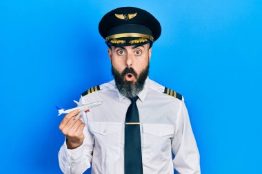 Pilot üniforması giyen genç İspanyol adam uçak oyuncağı tutuyor. Şaşırtıcı bir şekilde ağzı açık ve korkmuş, inançsız bir yüz. 