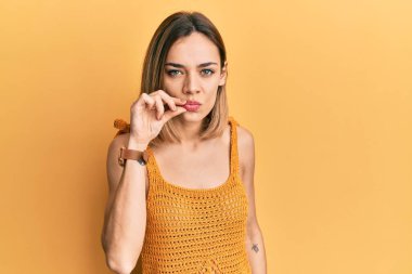 Sarışın, gündelik sarı tişört giyen genç, beyaz bir kadın ağzı ve dudakları parmaklarıyla fermuar gibi kapalı. gizli ve sessiz, tabu konuşması 