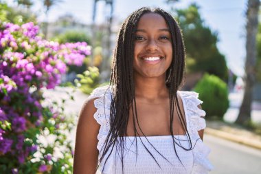 Genç Afrikalı Amerikalı kız gülümseyerek şehirde mutlu mesut duruyor..