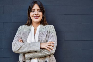 Genç İspanyol iş kadını şehirde çapraz hareketlerle mutlu gülümsüyor..