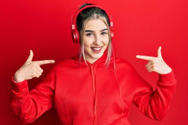 Spor kıyafetleri giyen, kulaklık takan, kendine güvenen, gülümseyen, kendini gururlu ve mutlu gösteren genç modern bir kız.. 