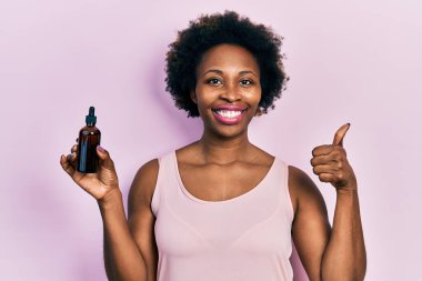 Yüzünde mutlu ve pozitif bir gülümseme olan Afro-Amerikalı genç bir kadın, başparmağıyla mükemmel ve onay işareti yapıyor. 