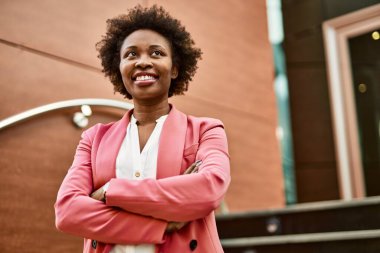 Güzel bir iş adamı Afro saçlı Amerikalı kadın şehirde mutlu ve kendinden emin bir şekilde gülümsüyor.