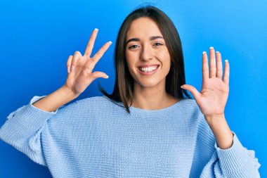 Gündelik kıyafetler giyen genç İspanyol kız gülümseyerek kendinden emin ve mutlu bir şekilde sekiz numarayı gösteriyor ve işaret ediyor.. 