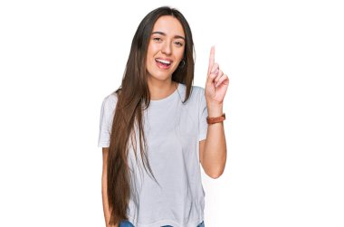 Gündelik beyaz tişört giyen genç İspanyol kız başarılı bir fikri işaret ediyor. Heyecanlı ve mutlu. Bir numara.. 