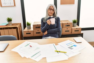 Ofiste çalışırken gülümseyen beyaz saçlı iş kadını.