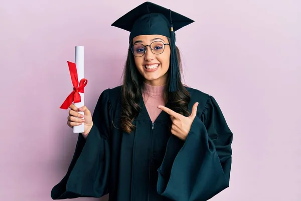 Jovem Hispânica Vestindo Uniforme Formatura Segurando Diploma Sorrindo Feliz Apontando — Fotografia de Stock